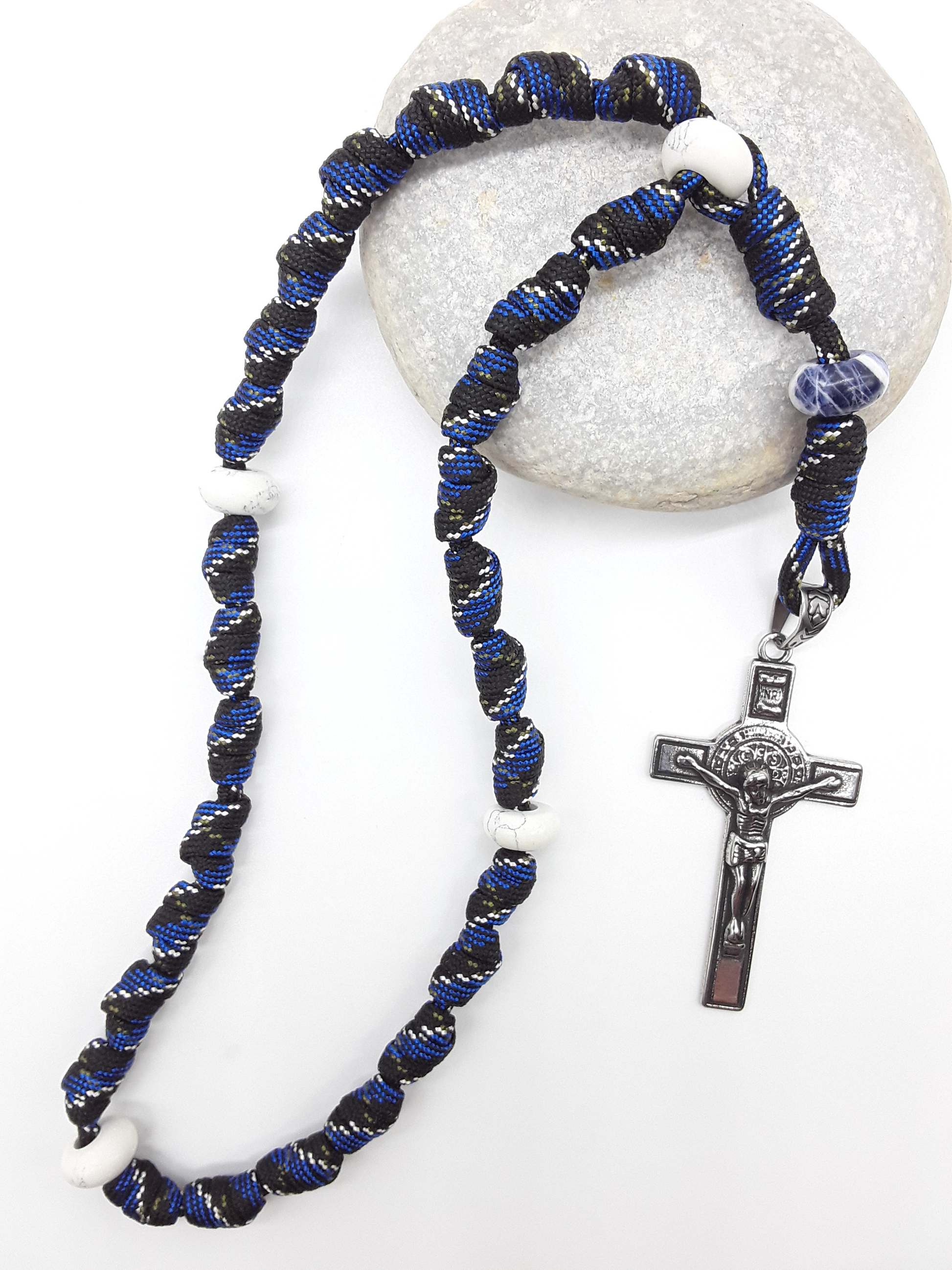 The Steady Witness Saint Benedict Anglican Rosary by Polmadeva with hand-knotted black and blue paracord, Howlite elements, and Saint Benedict Crucifix on stone.