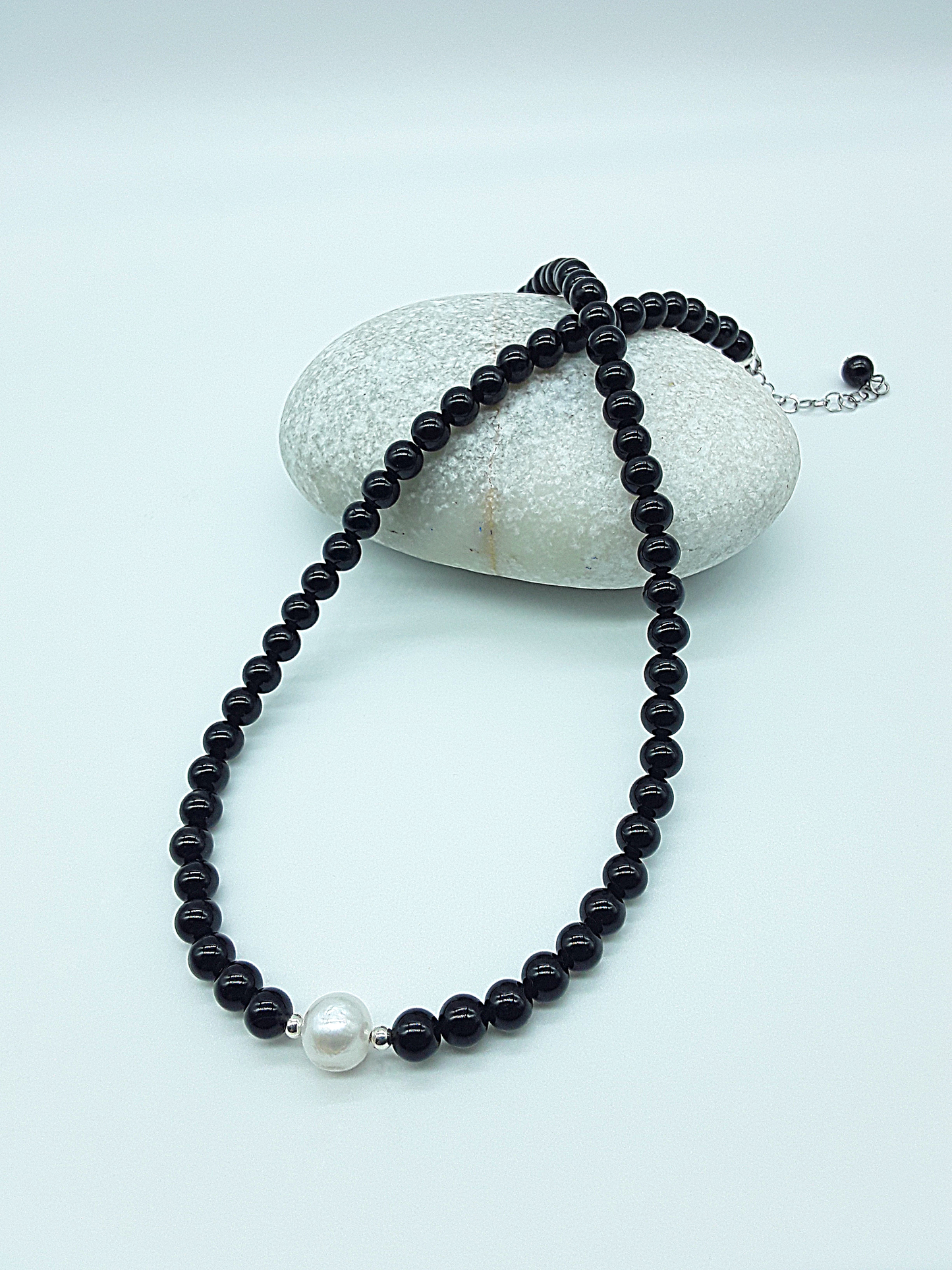 Still Core Necklace by Polmadeva with black onyx beads and single pearl draped over natural stone, Sacred Balance collection