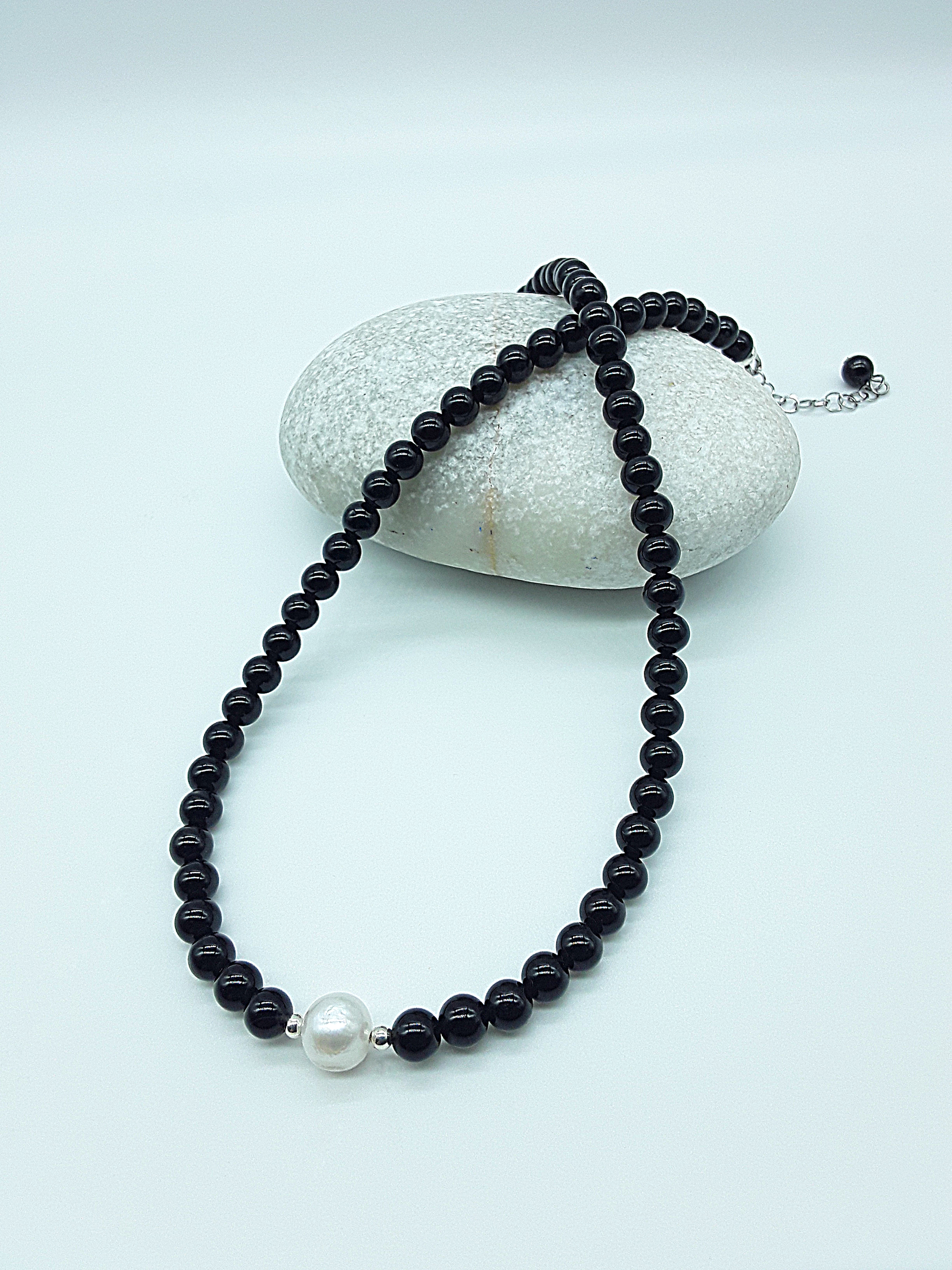 Still Core Necklace by Polmadeva with black onyx beads and single pearl draped over natural stone, Sacred Balance collection