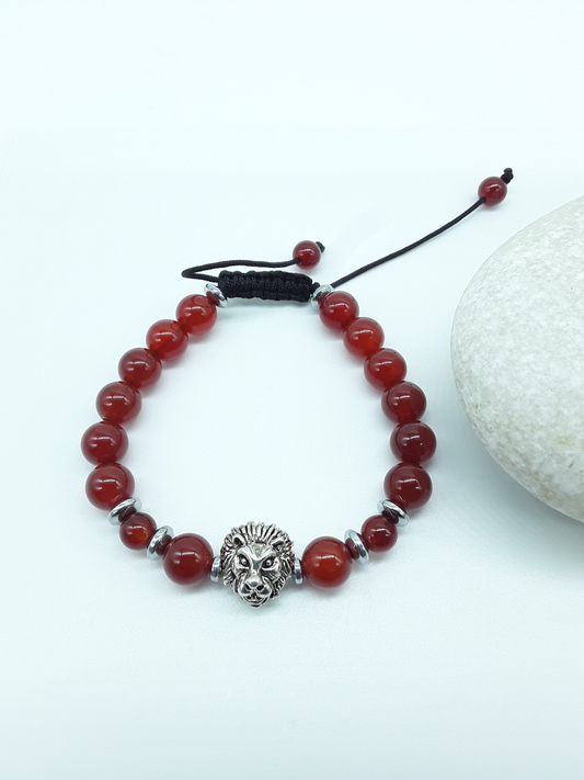 Carnelian and Hematite bracelet with lion element resting on natural stone, minimal editorial style
