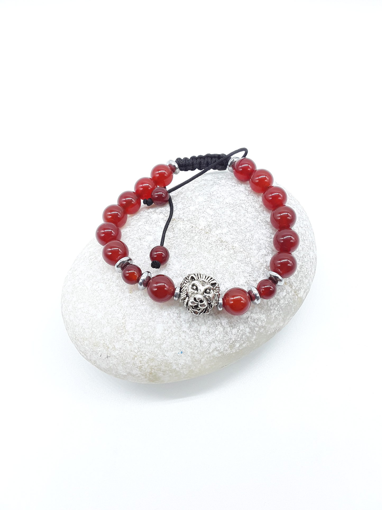Carnelian and Hematite bracelet with lion element resting on natural stone, minimal editorial style