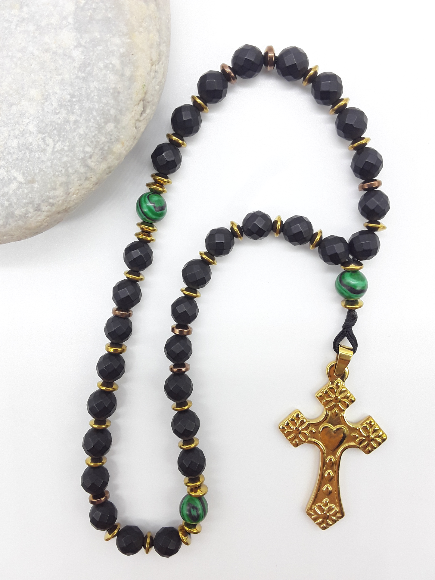 The Verdant Vigil — Black Onyx & Malachite Orthodox Rosary by Polmadeva, faceted black onyx beads with malachite accents and stainless steel cross, photographed beside natural stone to emphasize clarity, vigilance, and grounded presence.