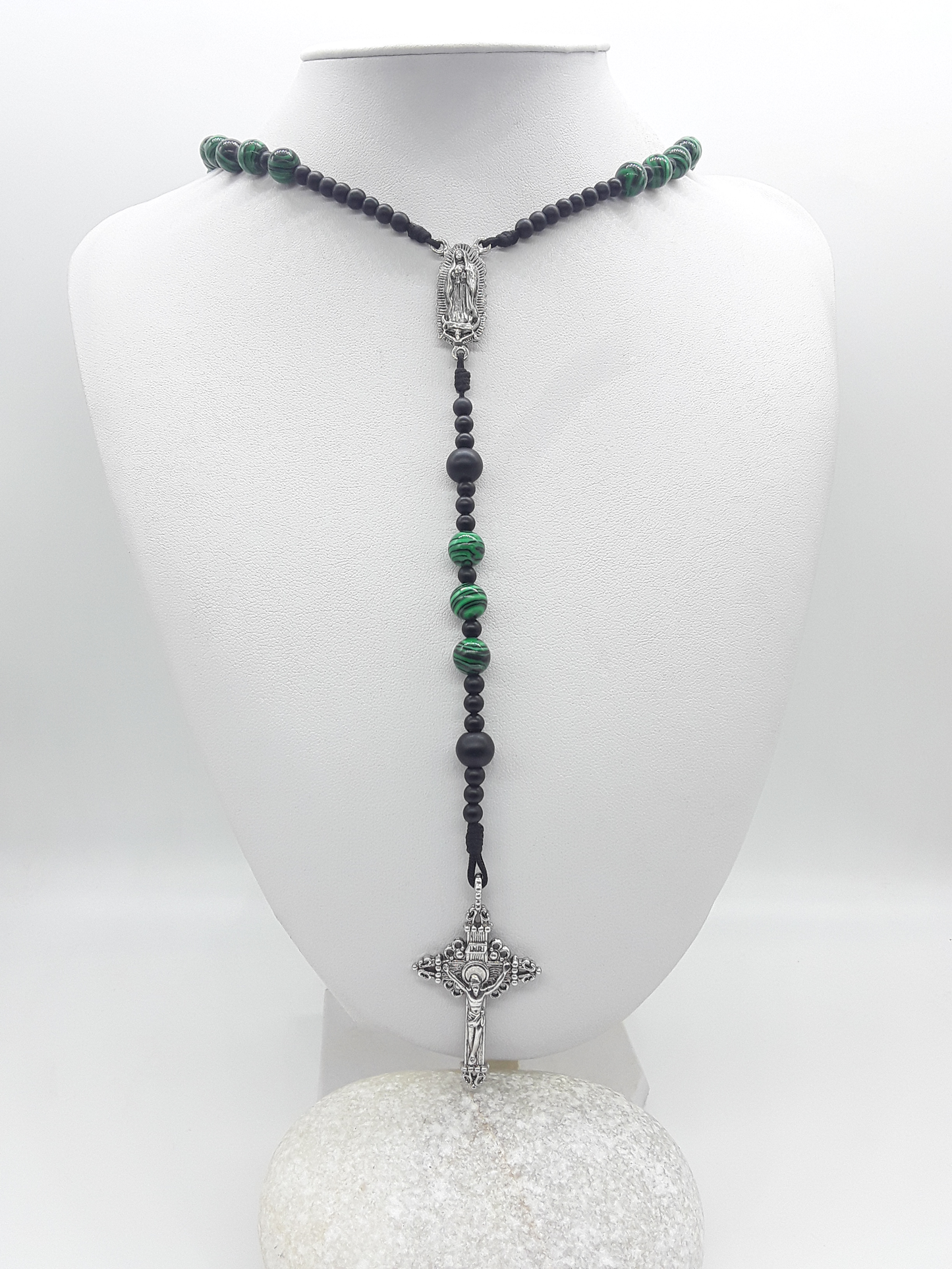 Catholic rosary with black onyx and malachite beads, featuring Our Lady of Guadalupe medallion and a silver-toned crucifix, displayed on a mannequin bust.
