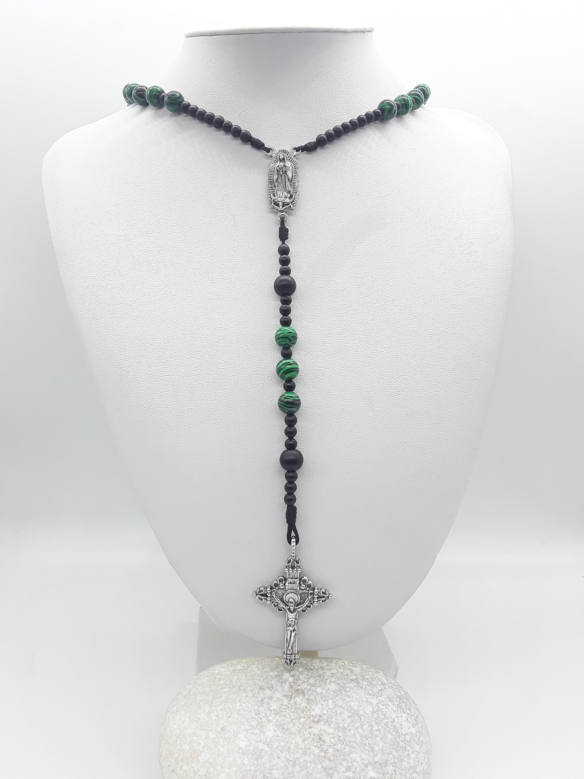 Catholic rosary with black onyx and malachite beads, featuring Our Lady of Guadalupe medallion and a silver-toned crucifix, displayed on a mannequin bust.