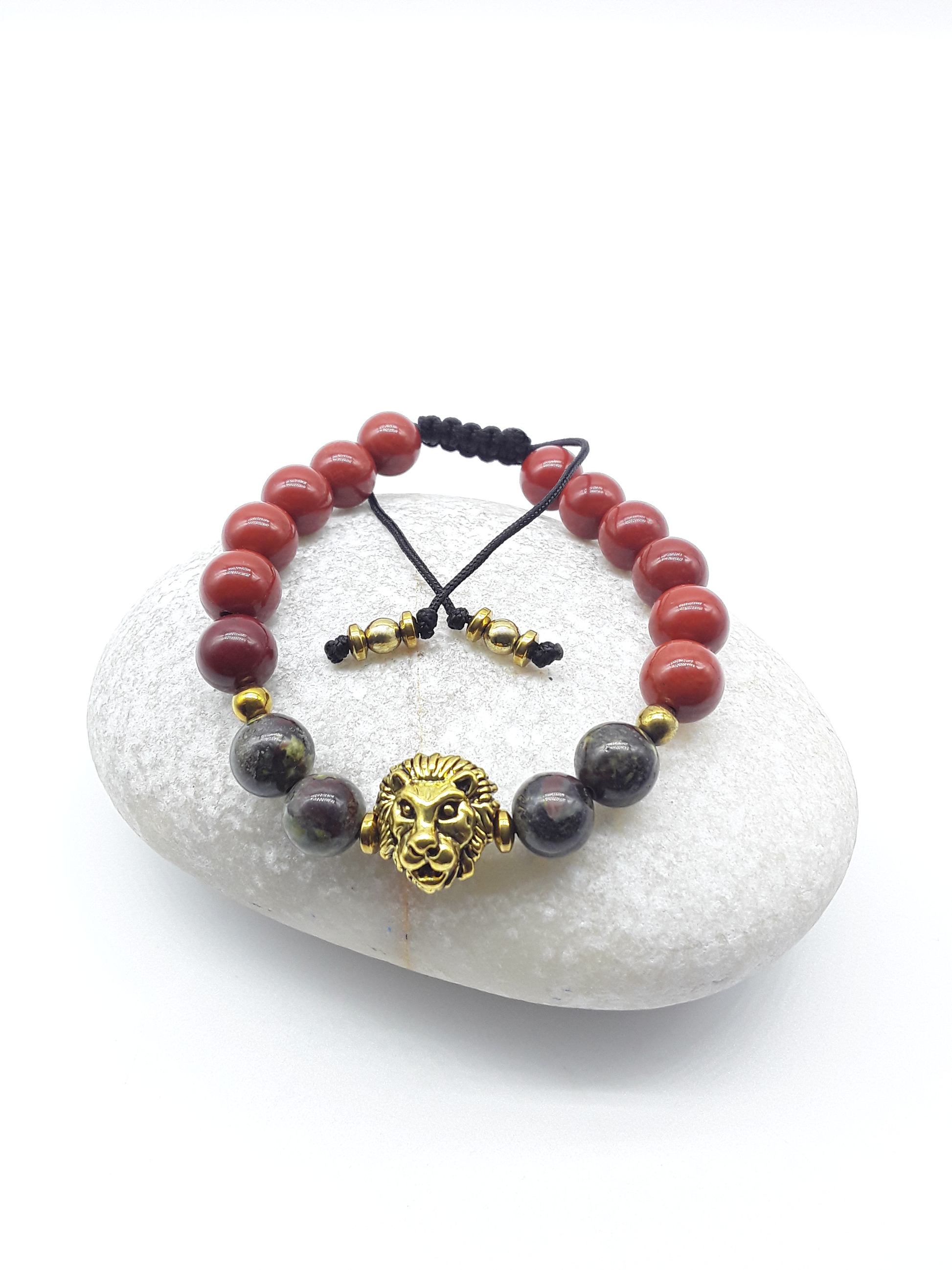 Lion bracelet with red jasper and dragon blood stones resting on a natural stone surface