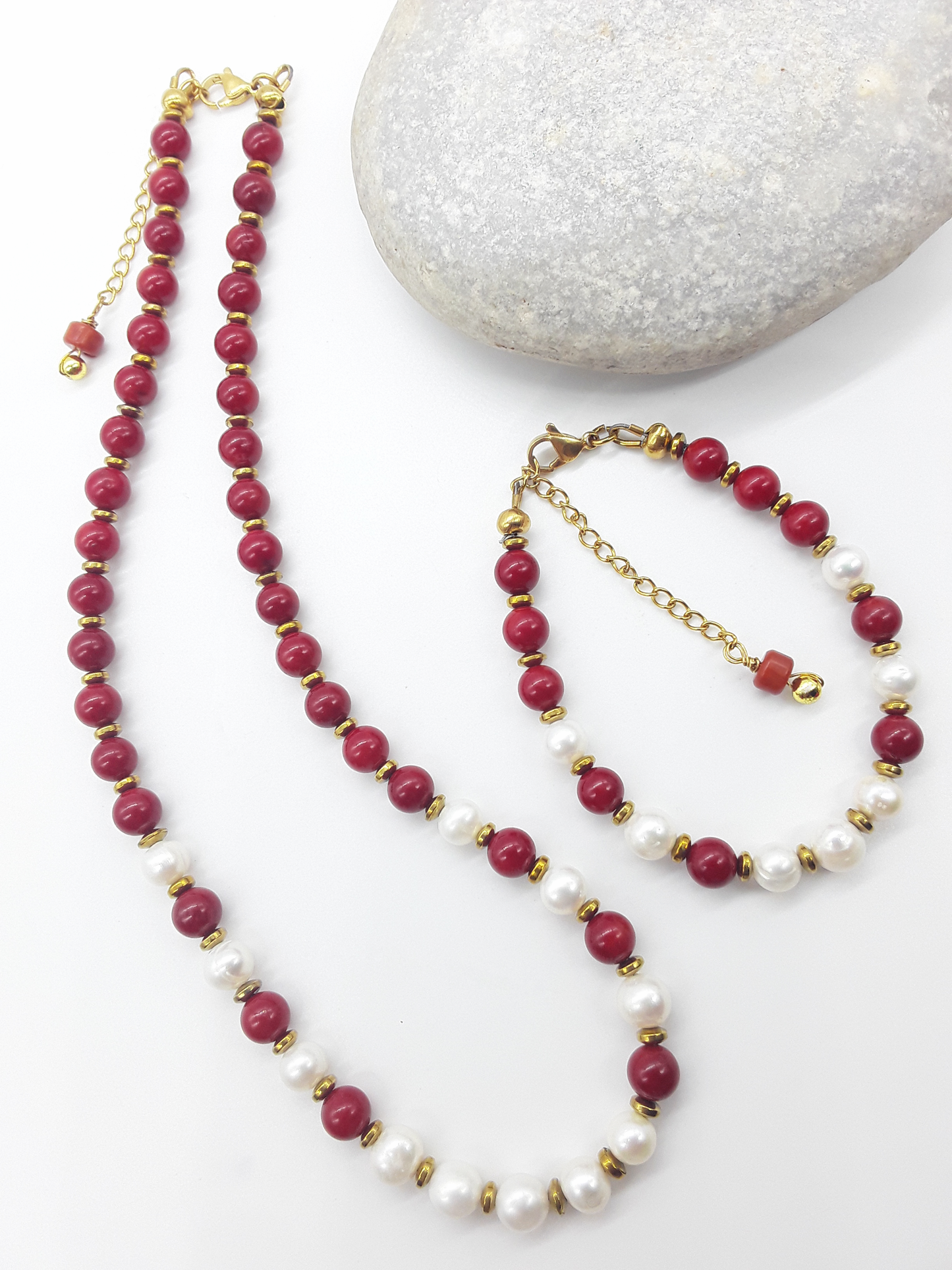 Where Grace Begins coral, freshwater pearl and hematite necklace with matching bracelet displayed beside a natural stone by Polmadeva
