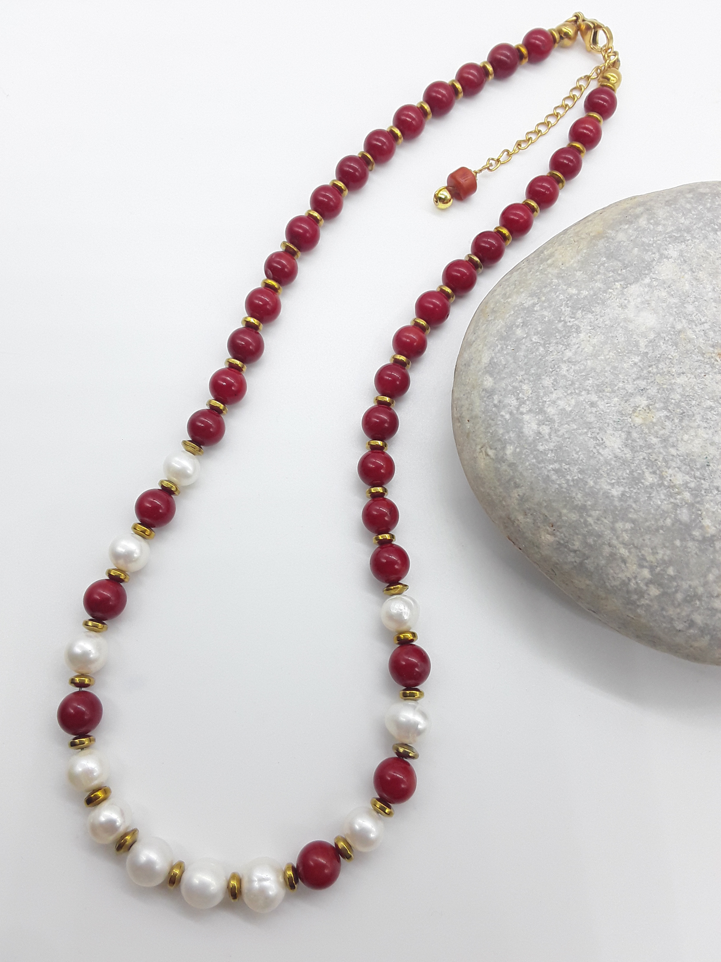 Where Grace Begins coral, freshwater pearl and hematite necklace beside stone by Polmadeva