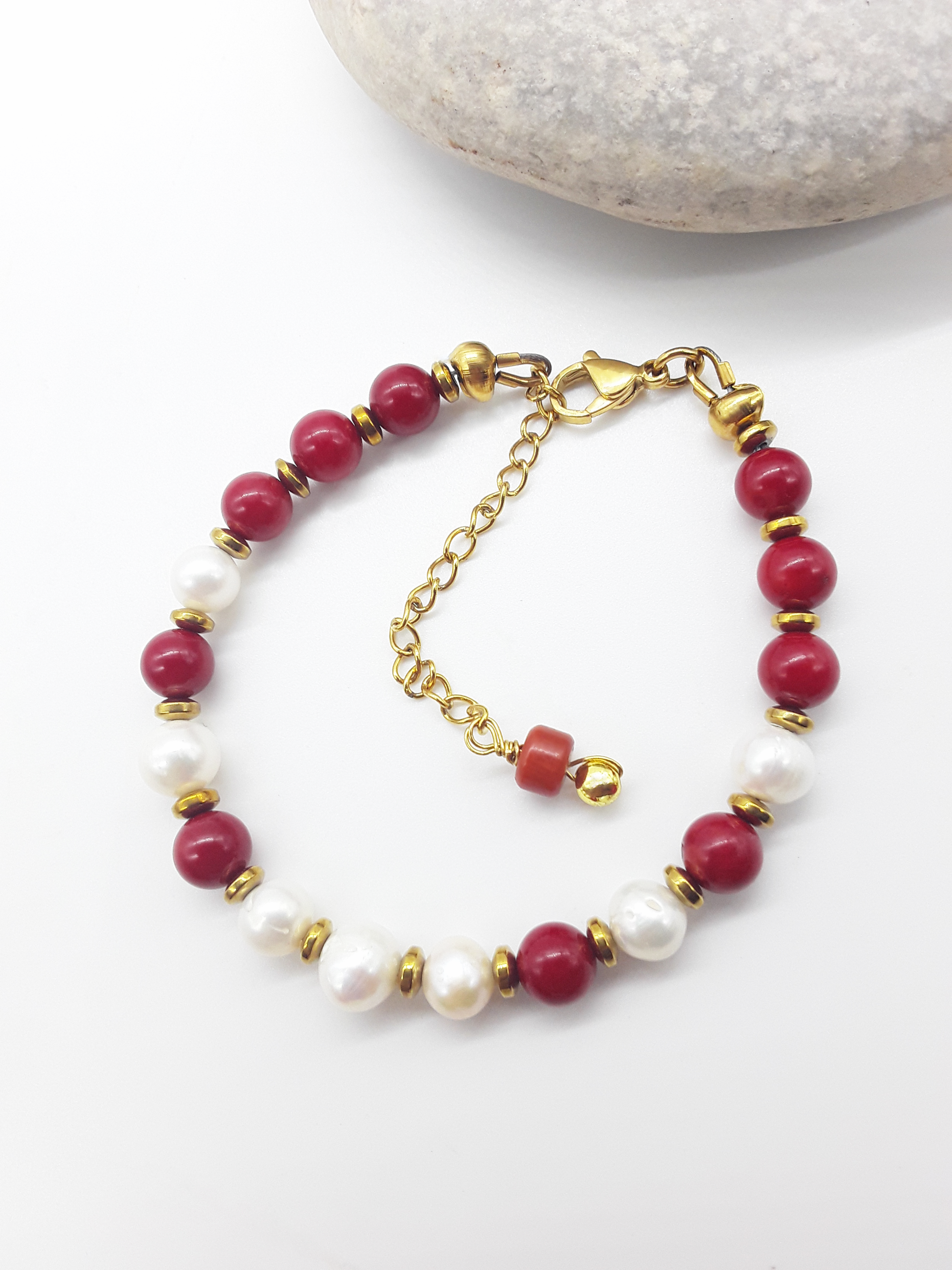Where Grace Begins coral, freshwater pearl and hematite bracelet beside stone by Polmadeva